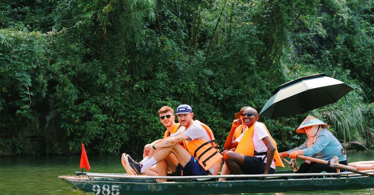 N'dalatando Travel Guide: Planning Tips, Costs and Things to Do Group enjoying a boat ride in lush Hoa Lư, Vietnam, amidst vibrant greenery.